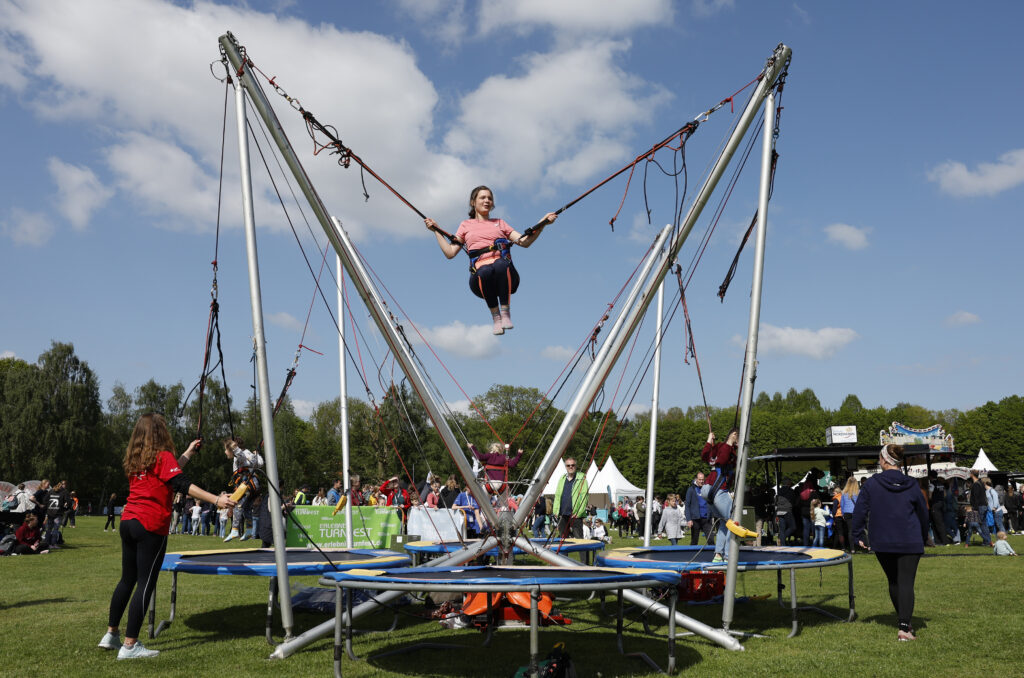 Ein Mädchen springt gesichert an Seilen auf einem Bungee-Trampolin in die Höhe.