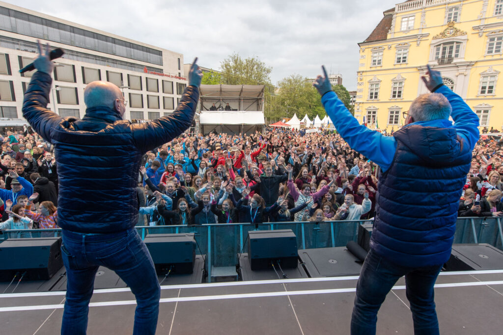 Moderatoren begeistern eine große Menschenmenge bei einer Mitmachaktion auf dem Stadtfestgelände