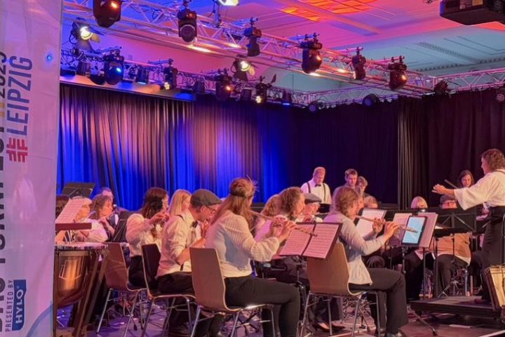 Dirigentin leitet Blasorchester auf violett beleuchteter Festivalbühne