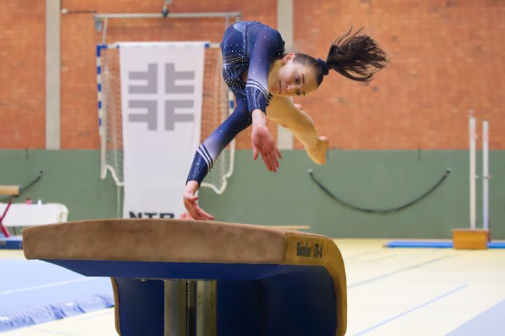 Turnerin führt einen Sprung über den Sprungtisch während eines Wettkampfs in der Sporthalle aus.