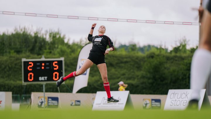 Faustballspielerin springt zum Angriffsschlag während eines Wettkampfs auf dem Sportplatz