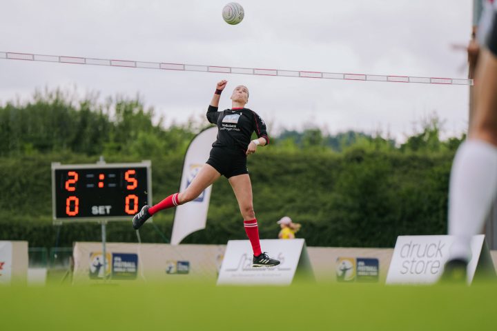 Faustballspielerin springt zum Angriffsschlag während eines Wettkampfs auf dem Sportplatz
