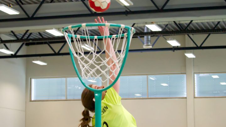 Korbballspielerin versucht den Ball während eines Hallenspiels in den Korb zu werfen.