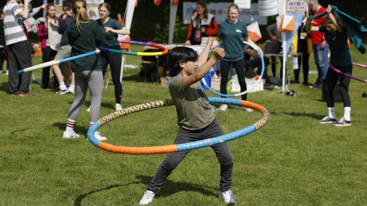 Junge, der auf einer Rasenfläche mit einem bunten Hula Hoop Reifen schwingt