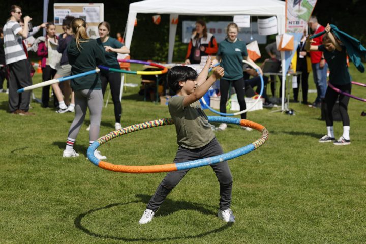 Junge, der auf einer Rasenfläche mit einem bunten Hula Hoop Reifen schwingt