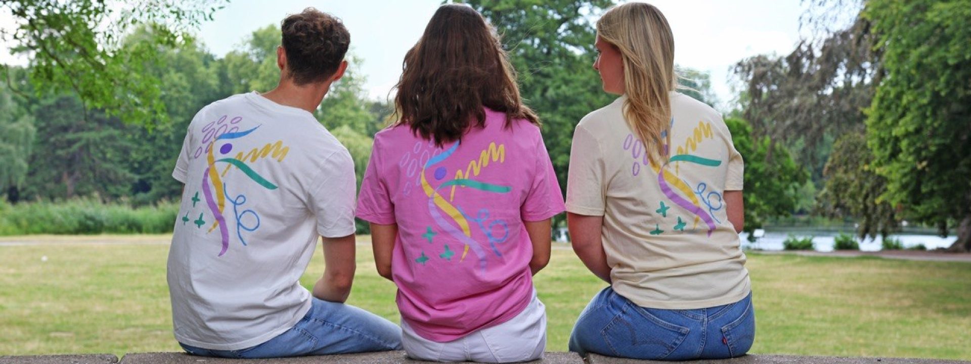 Drei Personen zeigen die Rückseiten der Turnfest-T-Shirts in Weiß, Pink und Pastellgelb